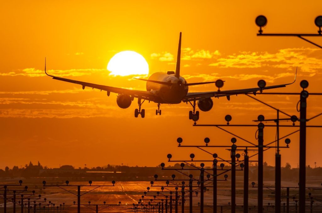 Passenger jet coming in to land at sunset over the runway lights