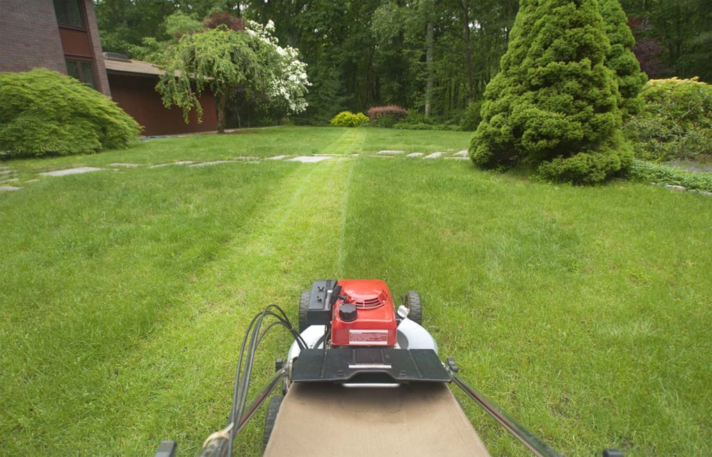 Riding mower cutting straight stripes across a lawn