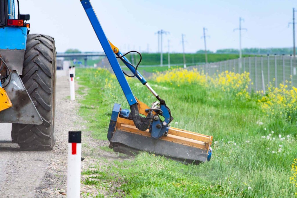 Tractor-mounted mower cutting a roadside strip